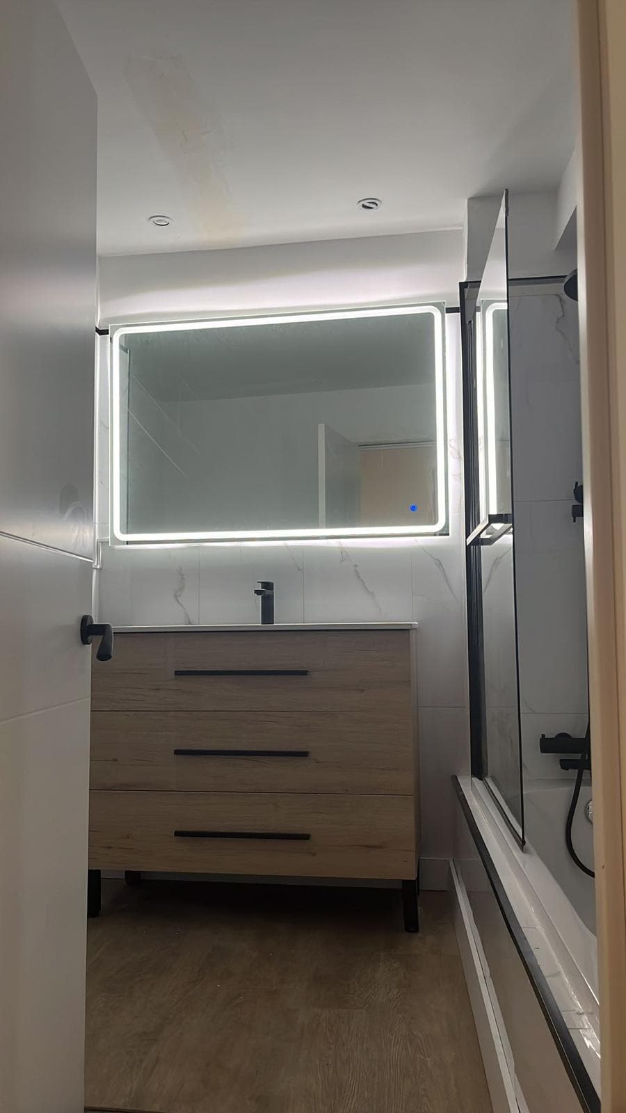 Baño reformado con revestimientos nuevos y buena iluminación